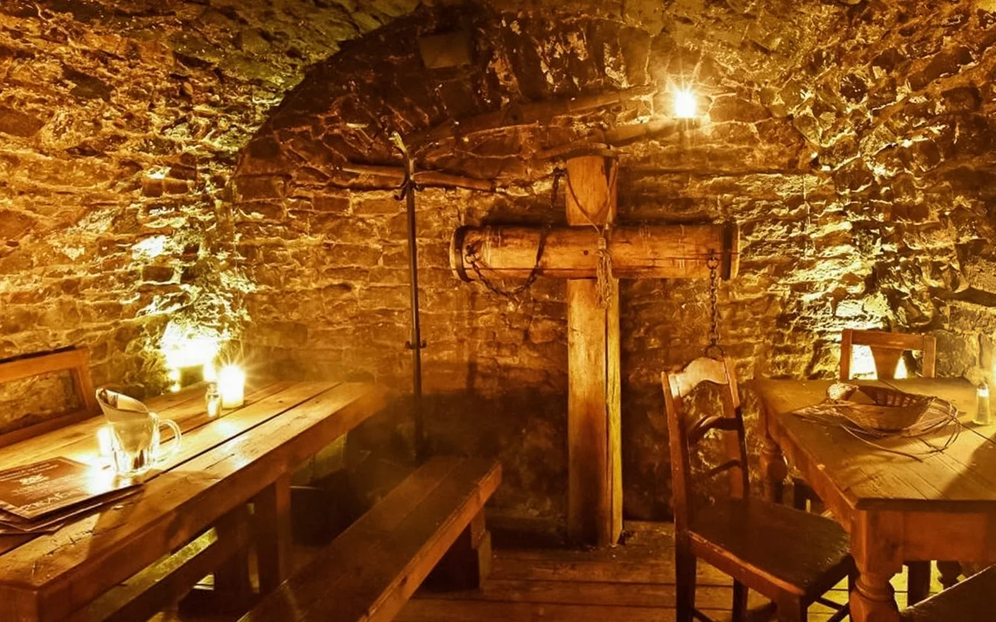 Rustic wooden seating beneath a vaulted stone ceiling in the tavern
